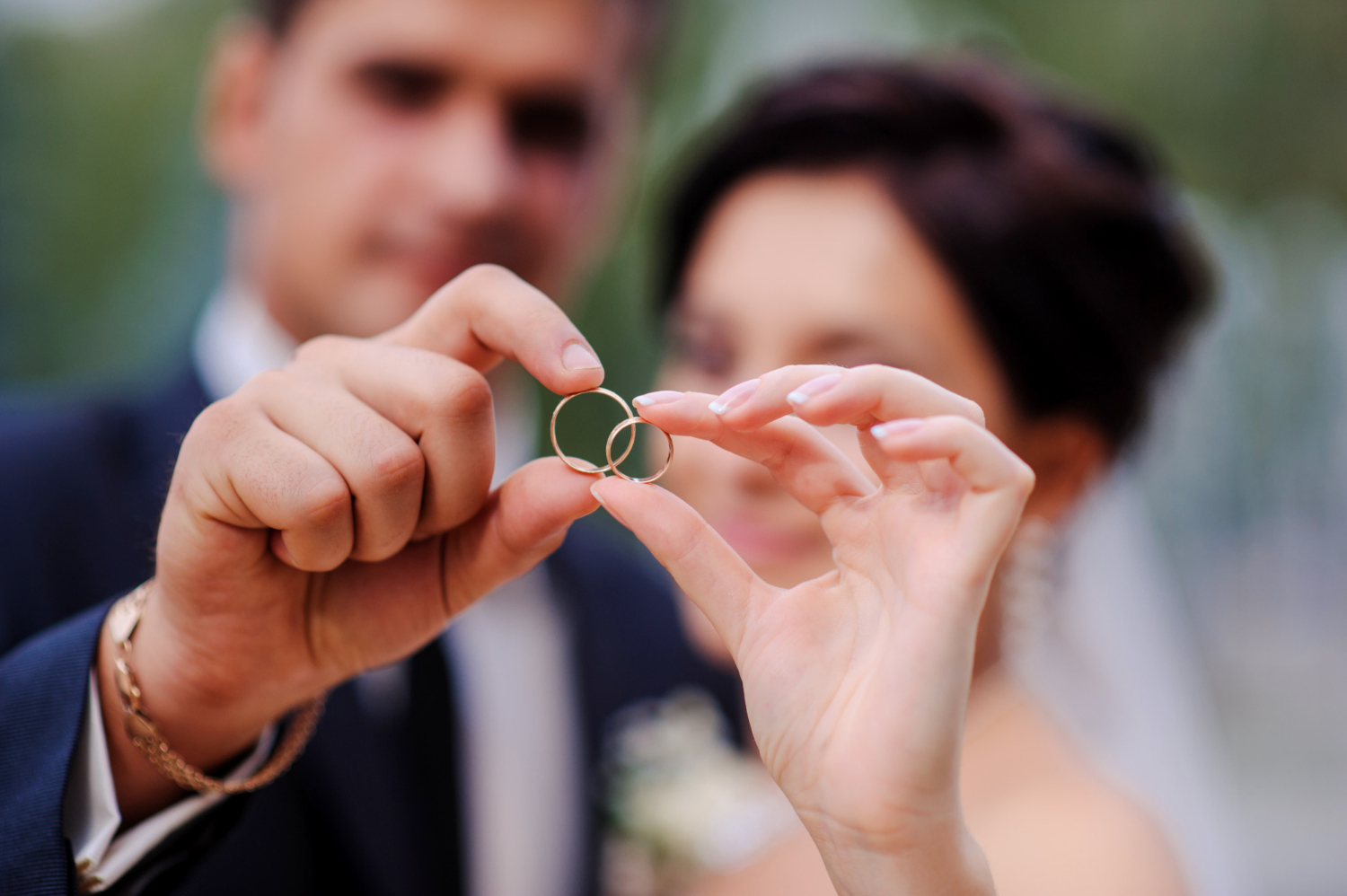 Photo bride and groom holding hands in a ring